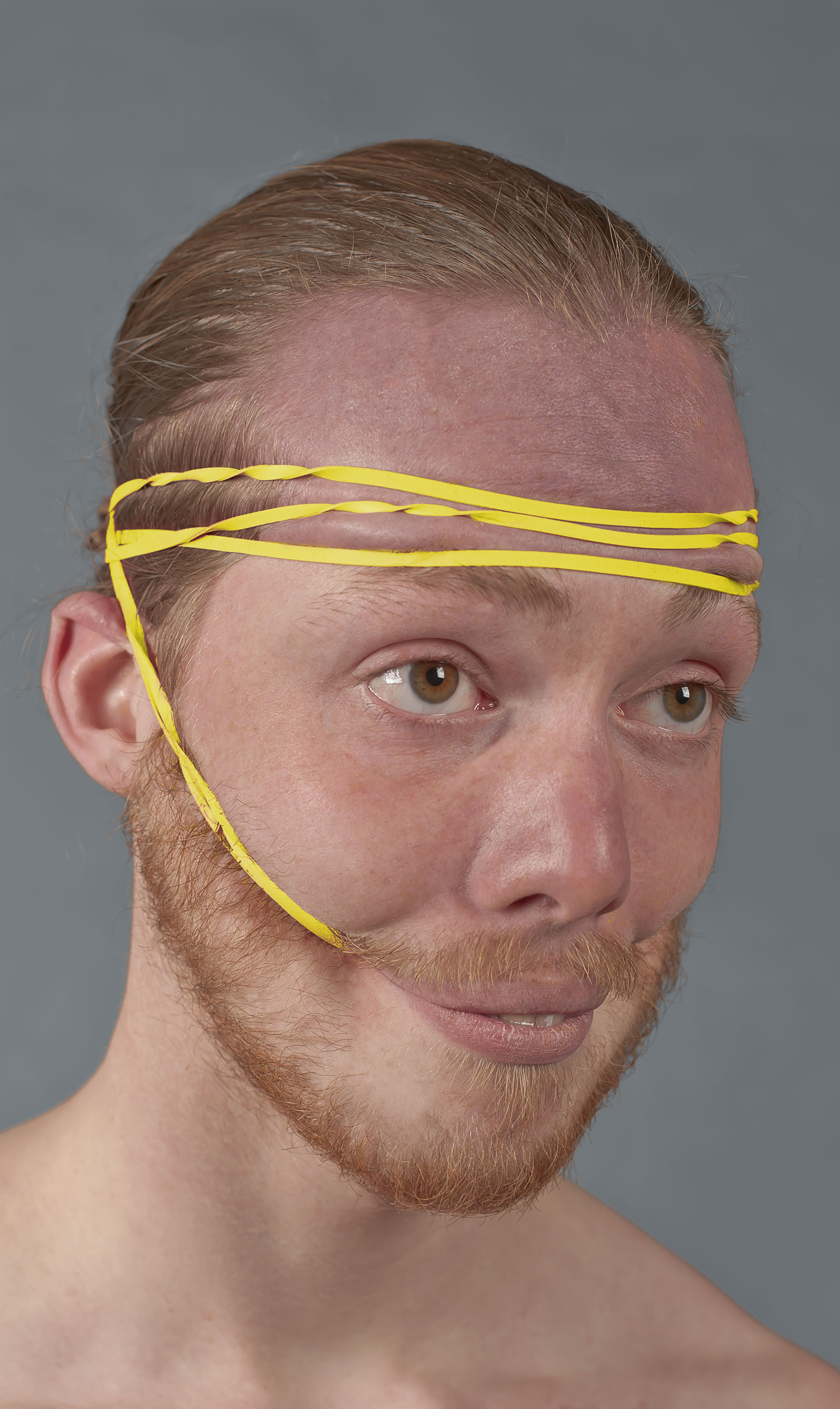 Portret met gele elastieken om het gezicht in een lachende houding te fixeren