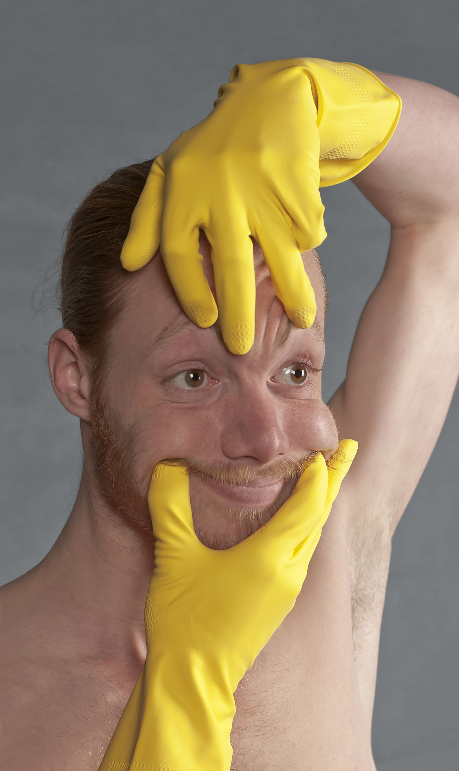 Portret met gele handschoenen die het gezicht in een lachende positie houden