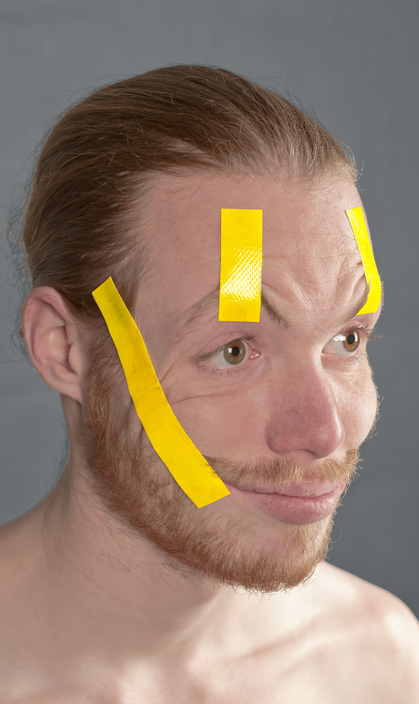 Portret met gele tape om gezicht in een lachende houding te fixeren